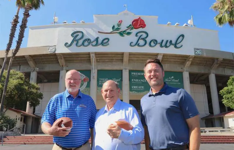three men posing in front of stadium